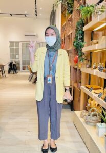 Perempuan karier duduk di kantor dengan outfit pastel yang simple tapi tetap fashionable dan percaya diri - Perempuan Daya
